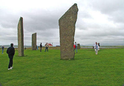 People standing on field against cloudy sky