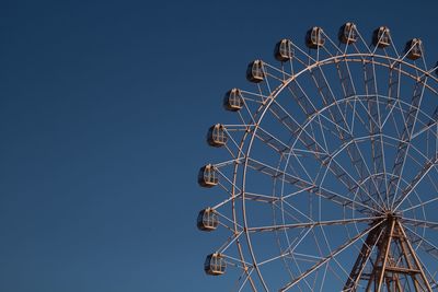 Low angle view of ferris wheel against clear blue sky