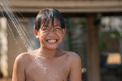 Close-up of shirtless boy standing by shower outdoors