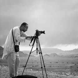 Man photographing on camera against sky