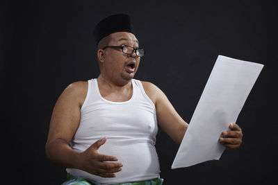 Mid adult man standing against black background