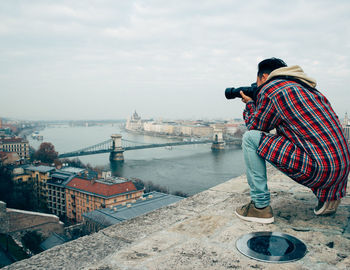 Man photographing city by river
