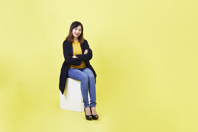Portrait of young woman against yellow background