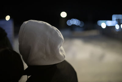 White hood and black jacket. man on street at night. cold light. unknown person in city at night.