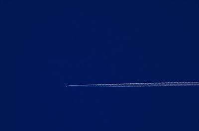 Low angle view of airplane flying against clear blue sky