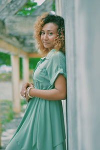 Portrait of smiling young woman standing by wall