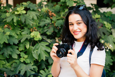 Portrait of smiling young woman holding camera