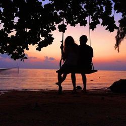Silhouette of people on beach at sunset
