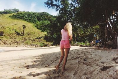 Rear view of woman walking on sand