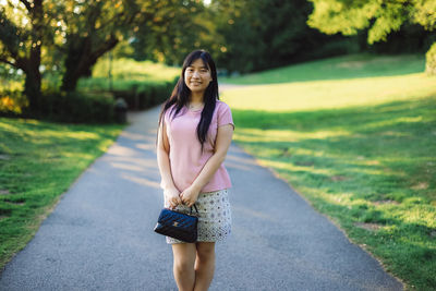 Full length portrait of young woman on road