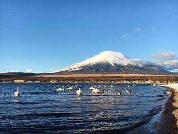 Scenic view of lake by mountains against clear blue sky