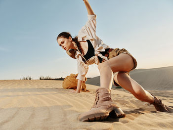 Full length of woman exercising on sand at beach