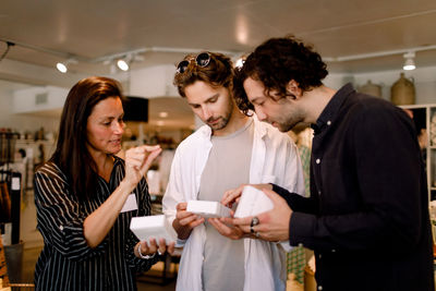 Saleswoman showing perfume box to male friends at store