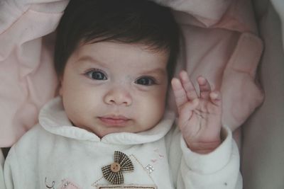 Close-up portrait of cute baby girl lying on bed