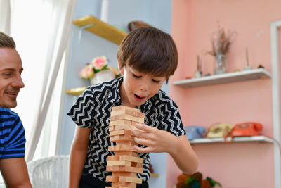 Boy stacking dominoes with father at home
