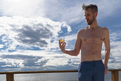 Shirtless man standing at seaside