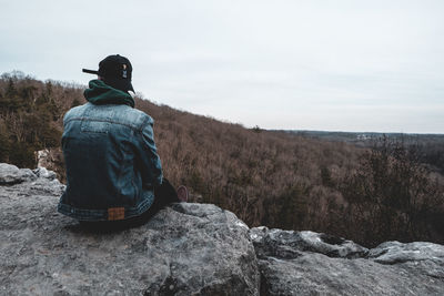 Rear view of man sitting on rock