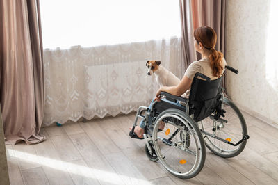 Side view of woman using mobile phone while sitting on sofa at home