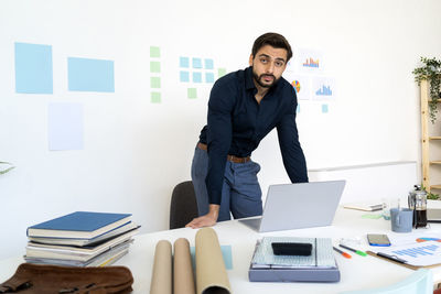 Young man using mobile phone while sitting on table