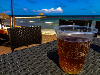 Close-up of coffee on table at beach against sky