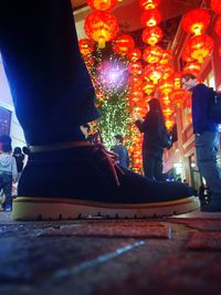 Low section of people standing on illuminated christmas lights at night