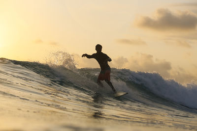 Young man man surfing at sunset