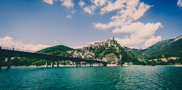 Bridge over river against cloudy sky