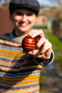 Closeup of one colored red egg, easter holiday concept. young person holding modern painted easter