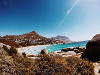 Panoramic view of sea and mountains against blue sky