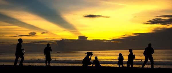 Silhouette of people on beach at sunset