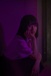 Young woman looking away against black background