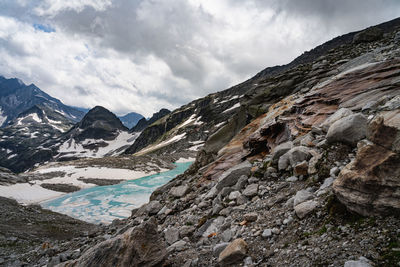 Scenic view of mountains, glacier and lake against cloudy sky