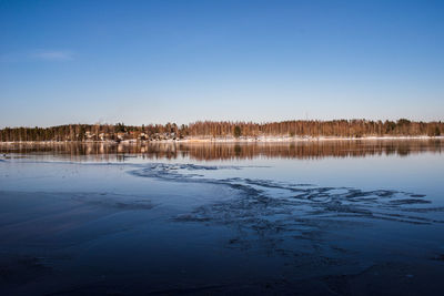 Scenic view of lake against clear blue sky during winter