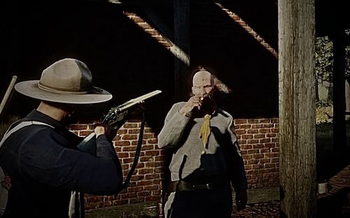 Man holding hat standing against wall at night