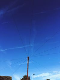 Low angle view of power cables against blue sky