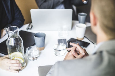 Midsection of business colleagues sitting at board room during office meeting