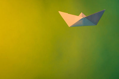 Close-up of paper boat with smoke against green background