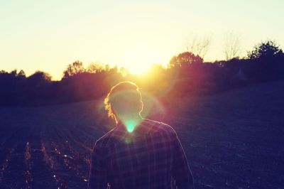 Man standing on field against sky during sunset