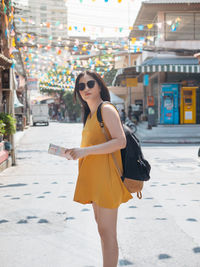 Side view of woman holding map while standing outdoors