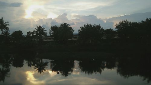 Silhouette trees by lake against sky during sunset