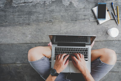 Midsection of man using mobile phone while sitting on table