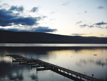 Pier on lake against cloudy sky