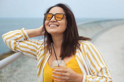 Portrait of young woman wearing sunglasses against sky