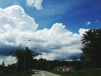 Road by trees against sky