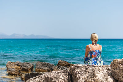 Rear view of woman looking at sea against clear sky