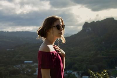 Side view of thoughtful woman standing against mountain