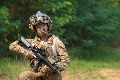 Young soldier holding gun outdoors