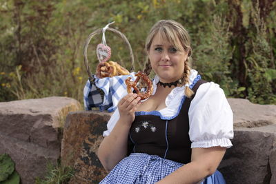 Portrait of overweight young woman holding pretzel bread