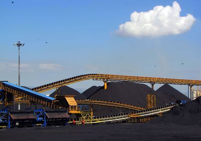 Low angle view of metallic structures at coal industry against sky