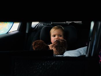 Baby boy with stuffed toy sitting in car
